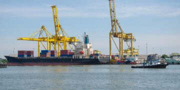 Cargo ship at maritime container dock representing regional trade and transport corridors.